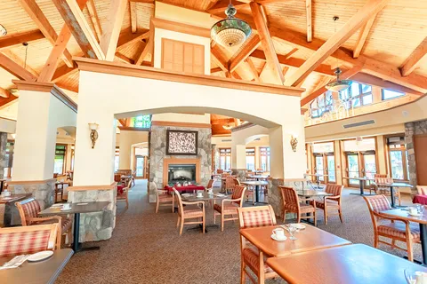 Dining room with set tables, upholstered chairs and a timber ceiling