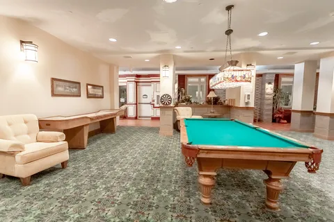 Room with a billiard table, shuffleboard table and chairs