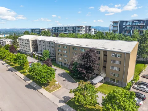 Aerial view of the residence with surrounding trees and parking.