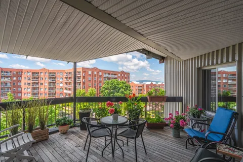 Covered balcony with outdoor table, chairs and flowerpots.