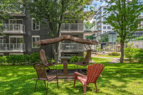 Covered garden swing and chairs on the lawn beside the building.