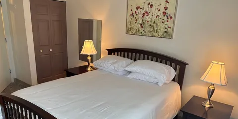 Bedroom with a wooden bed, two bedside lamps and floral wall art