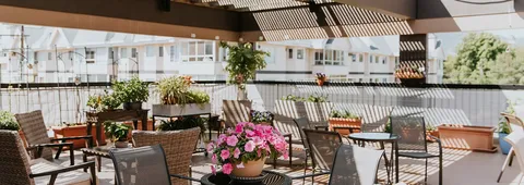 Rooftop patio with tables, chairs, flower planters and a pergola