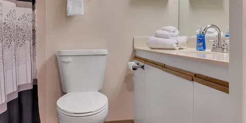 Bathroom with sink, mirror, toilet and folded towels