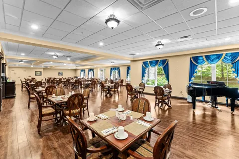 Dining room with wooden tables, chairs and a grand piano