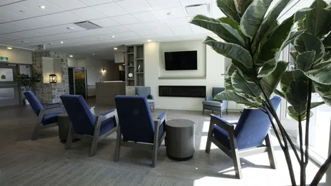 Common sitting area with blue armchairs and large windows.