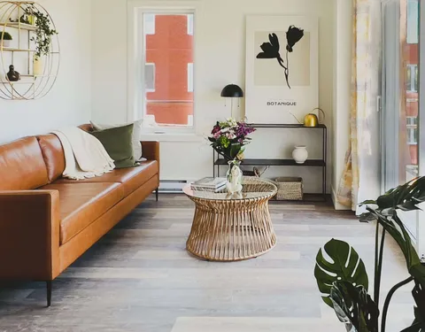 Suite sitting area with a leather sofa beside large windows.