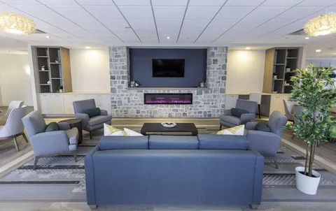Lounge with blue sofas, a stone fireplace and a television.