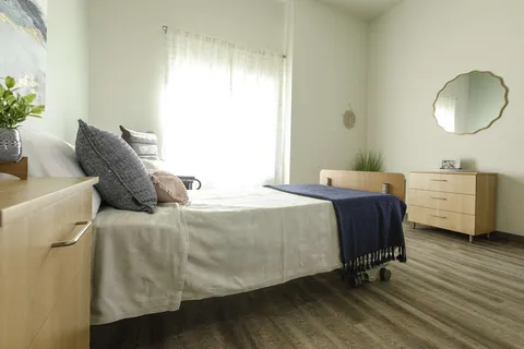 Accessible bedroom with an adjustable bed and an armchair.