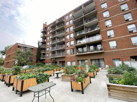 Residence balconies above a patio with raised vegetable and flower beds.