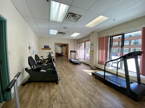 Exercise room with treadmills, seated exercise machines and windows.