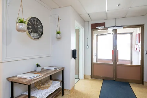 Glass entrance doors with signs and a floor mat