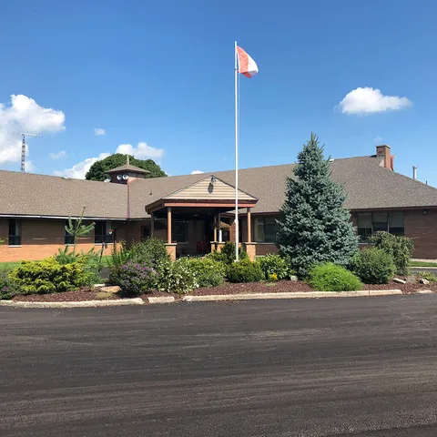 Building entrance with a covered porch, shrubs and a Canadian flag