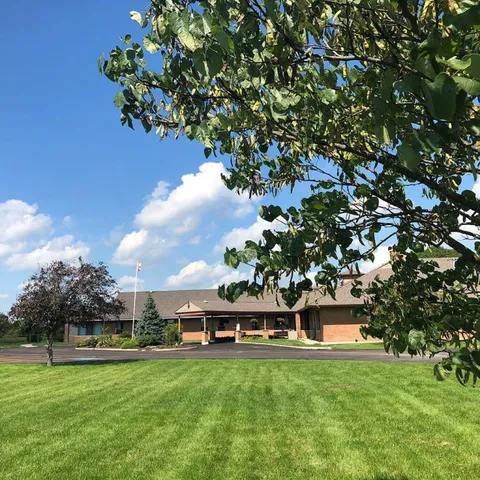House behind a broad lawn and a large shade tree