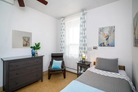 Bedroom with a blue bed cover, curtains and framed animal pictures