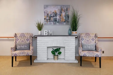 Armchairs around a white fireplace beneath a colourful painting