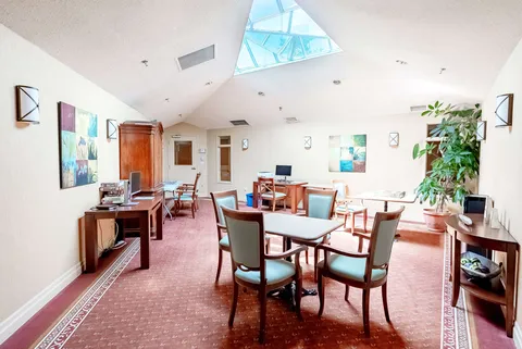 Room with tables, wooden chairs, wall art, a plant and a skylight