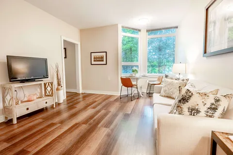 Sitting area with a cream sofa, television, dining table and corner windows
