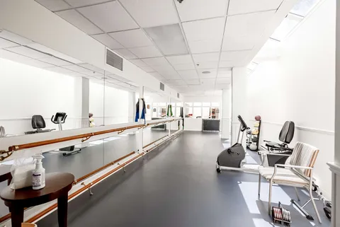 Exercise room with parallel bars, stationary bicycles, chairs and wall mirrors