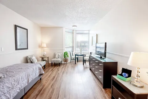 Bedroom with a single bed, armchairs, television, dresser and window
