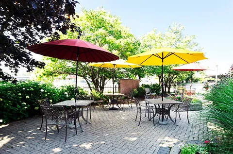 Brick patio with metal tables and chairs beneath colourful umbrellas