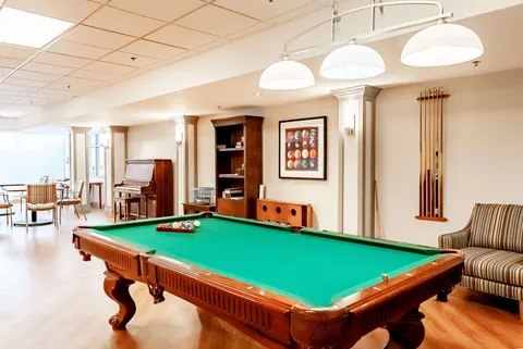 Games room with a billiards table, upright piano and striped armchair