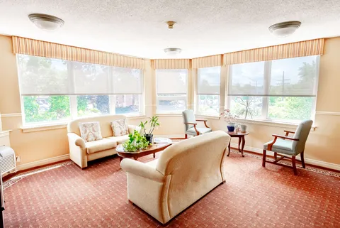 Seating area with cream sofas, armchairs, tables, plants and wide windows