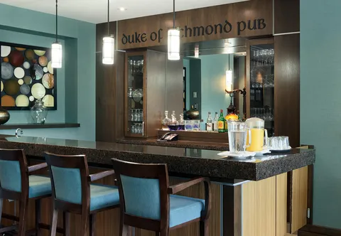 Pub bar with stools, bottles and glass-fronted cabinets.
