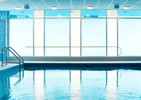 Indoor pool beside a broad wall of windows.