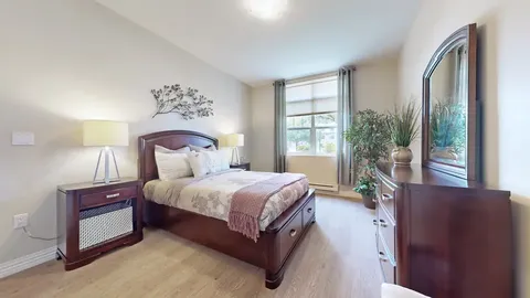Bedroom with a bed, bedside lamps, dresser and mirror