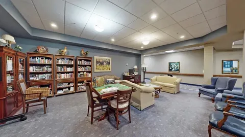 Library with bookshelves, sofas, armchairs and a game table