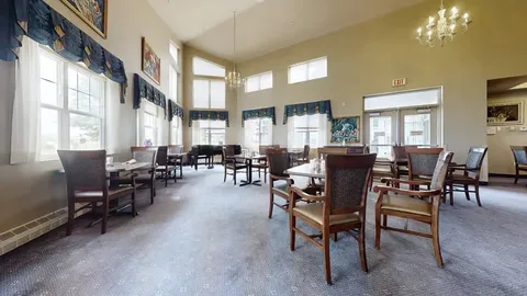 Dining room with tables, chairs, a piano and high windows