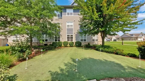 Putting green surrounded by trees and planted beds