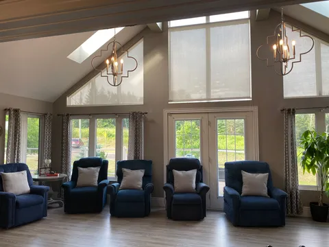 Bright room with blue recliners beneath tall windows and a vaulted ceiling