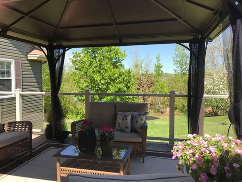 Covered outdoor seating area with wicker furniture and potted flowers