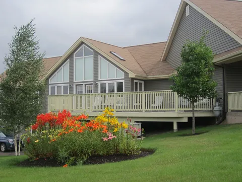 Residence exterior with a raised deck and bright flower beds