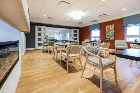 Room with tables, armchairs and a fireplace beside large windows