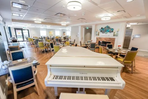 Dining room with tables, chairs, a fireplace and a white grand piano