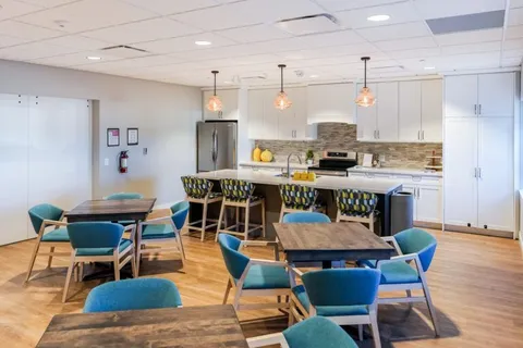 Kitchen with white cabinets, an island and blue upholstered chairs