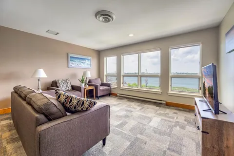 Room with a brown sofa, purple armchairs and large windows