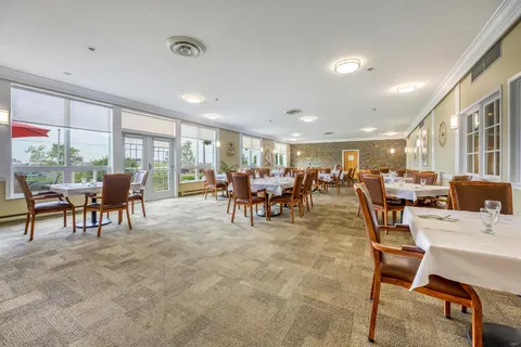 Dining room with white tablecloths, upholstered chairs and waterfront windows