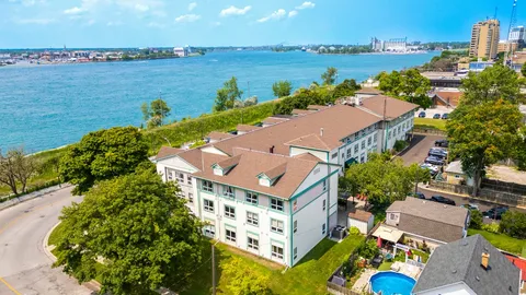 Aerial view of a brick residence beside a river and parking area