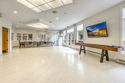 Activity room with a shuffleboard table, chairs and a television