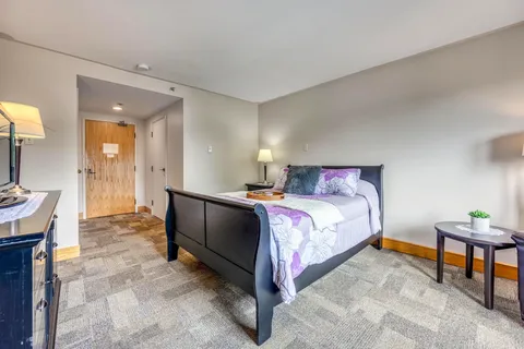 Bedroom with a dark bed frame, purple bedding and bedside tables