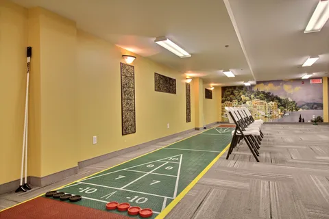 Indoor shuffleboard court beside a row of folding chairs.