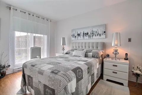 Bedroom with a grey bedspread and bedside tables.