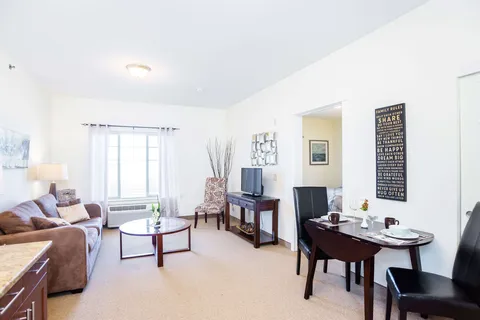 Sitting area with a sofa, television, coffee table and dining table beside a window