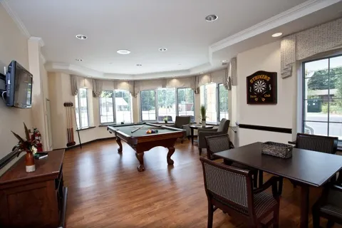 Billiard table and chairs beside wide windows, a wall-mounted television and a dartboard