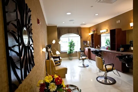 Salon with styling chairs, mirrors, dark wood cabinets and black shampoo basins