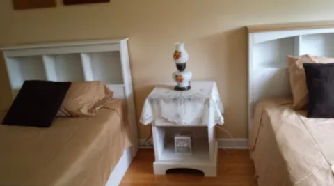 Two single beds with beige bedding beside a small white nightstand